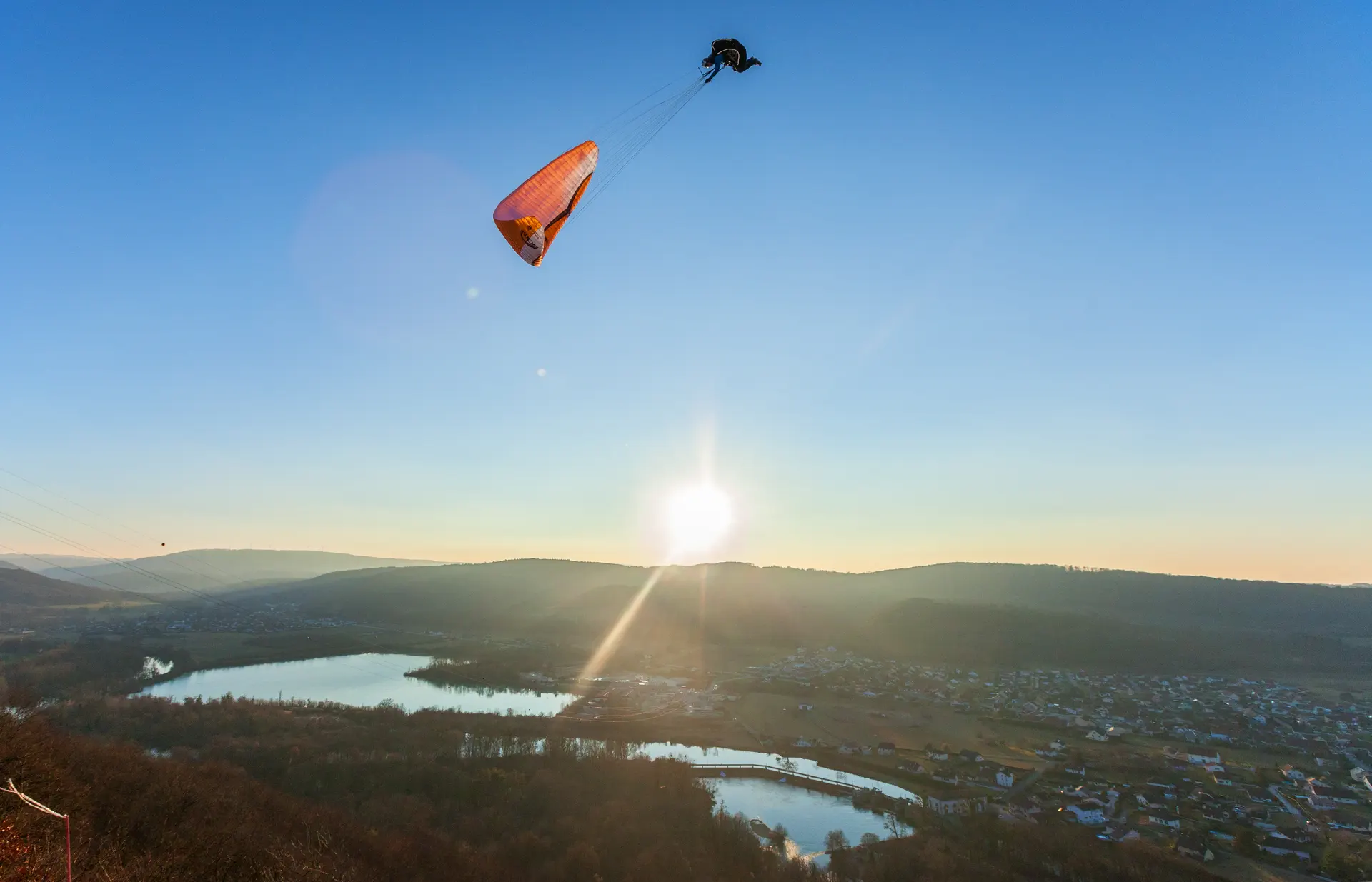 Vol biplace parapente au coucher du soleil – Stage et école – VolParapente.fr Vol en parapente biplace tandem au-dessus d’un lac en France au coucher du soleil avec une école de parapente.