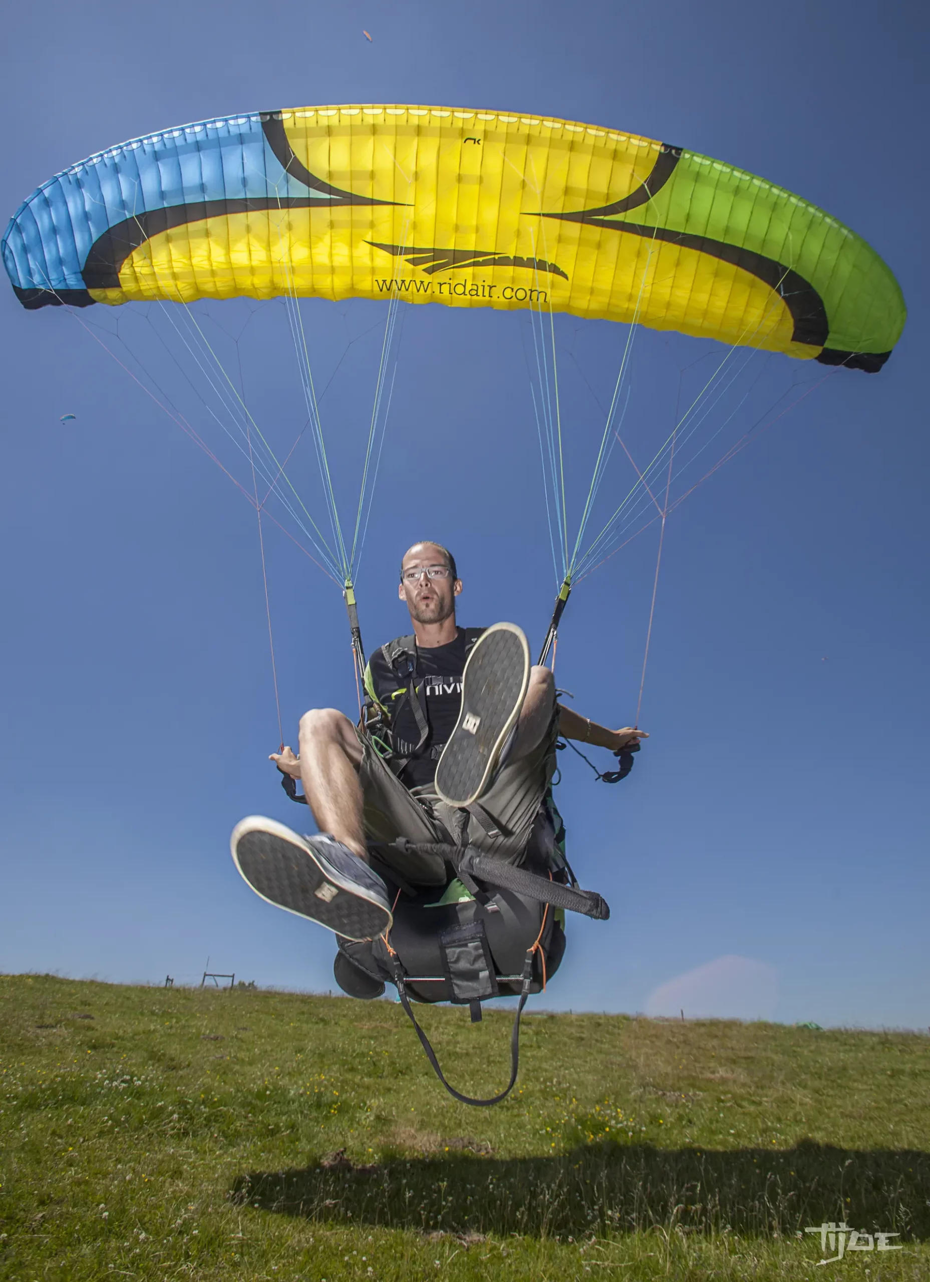 Stage et vol biplace en école de parapente – VolParapente.fr Vol en parapente biplace tandem lors d’un stage avec une école de parapente en France sous un ciel bleu.