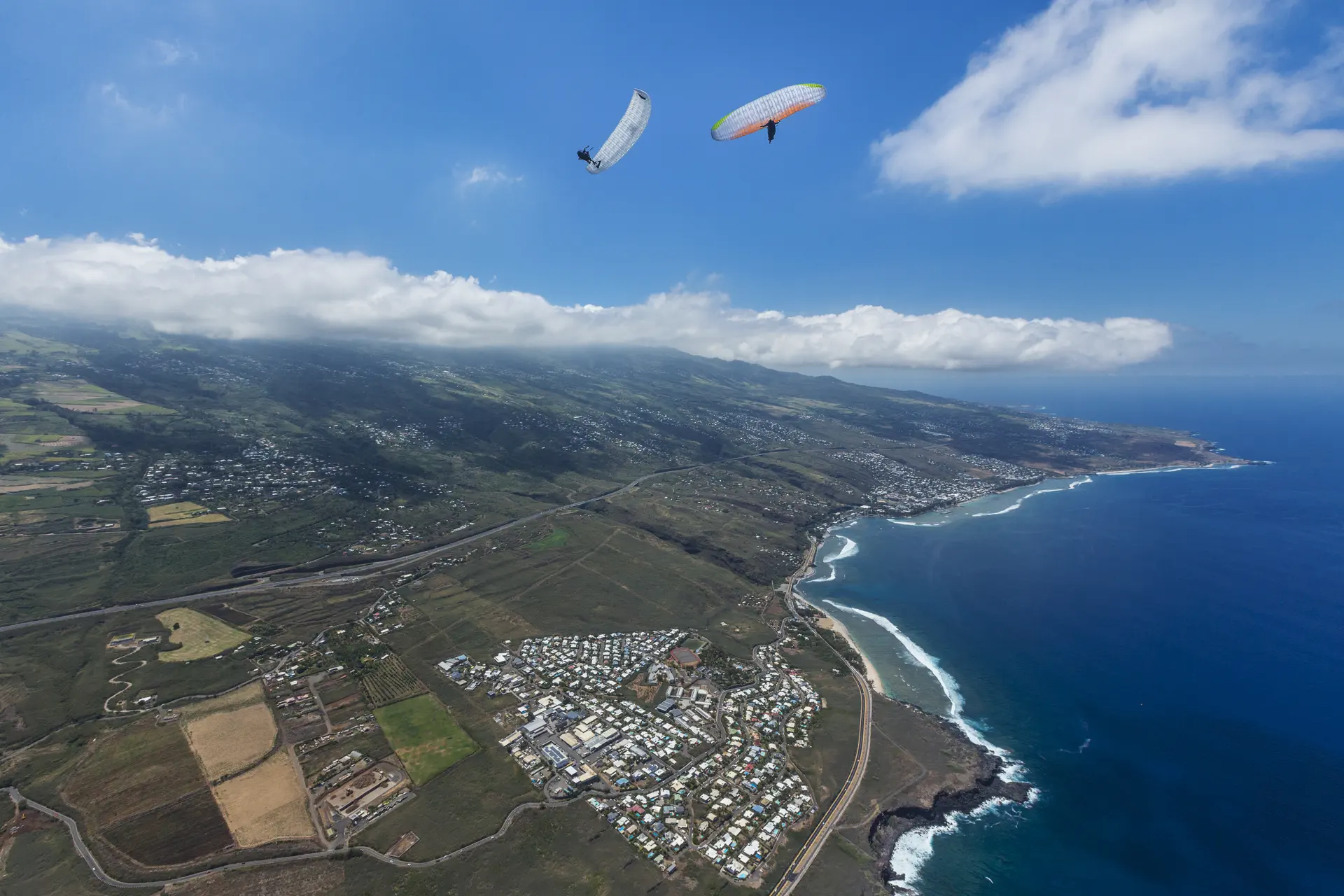 Vol parapente à La Réunion – Vue littoral et montagne – VolParapente.fr Vol parapente au-dessus du littoral de La Réunion, entre mer et montagnes, avec une école de parapente.