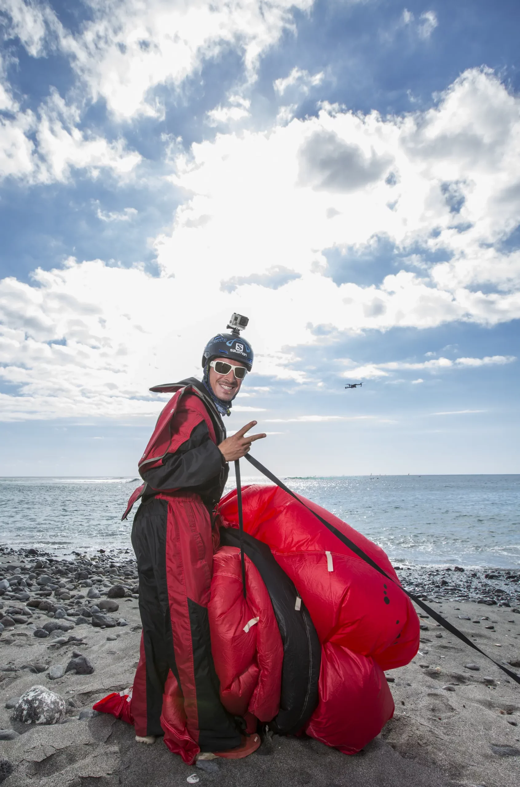 Pilote parapente biplace à La Réunion – École et vol tandem – VolParapente.fr Pilote de parapente à La Réunion sur la plage après un vol avec son aile rouge.